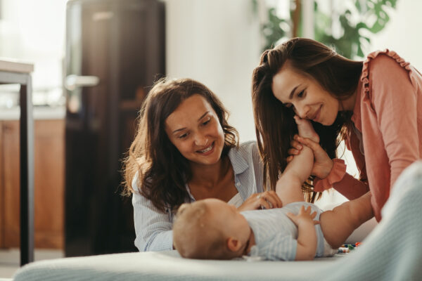 Loving lesbian couple playing with their baby while spending time together at home.