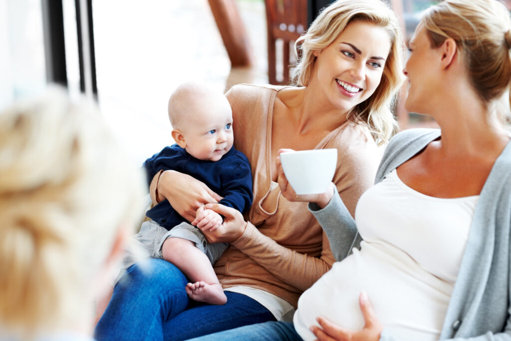 Happy pregnant woman with her friends relaxing at home - Indoors